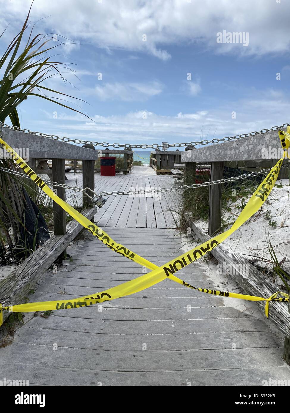 Caution tape, chains and lock blocking entrance to the beach due to closures and coronavirus April 2020 Florida USA - Smartphone Captured Stock Image