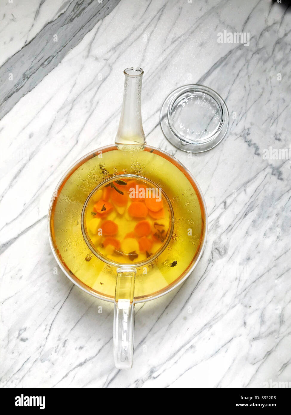 Glass teapot with turmeric and ginger steeping for immunity boosting tea - Smartphone Captured Stock Image