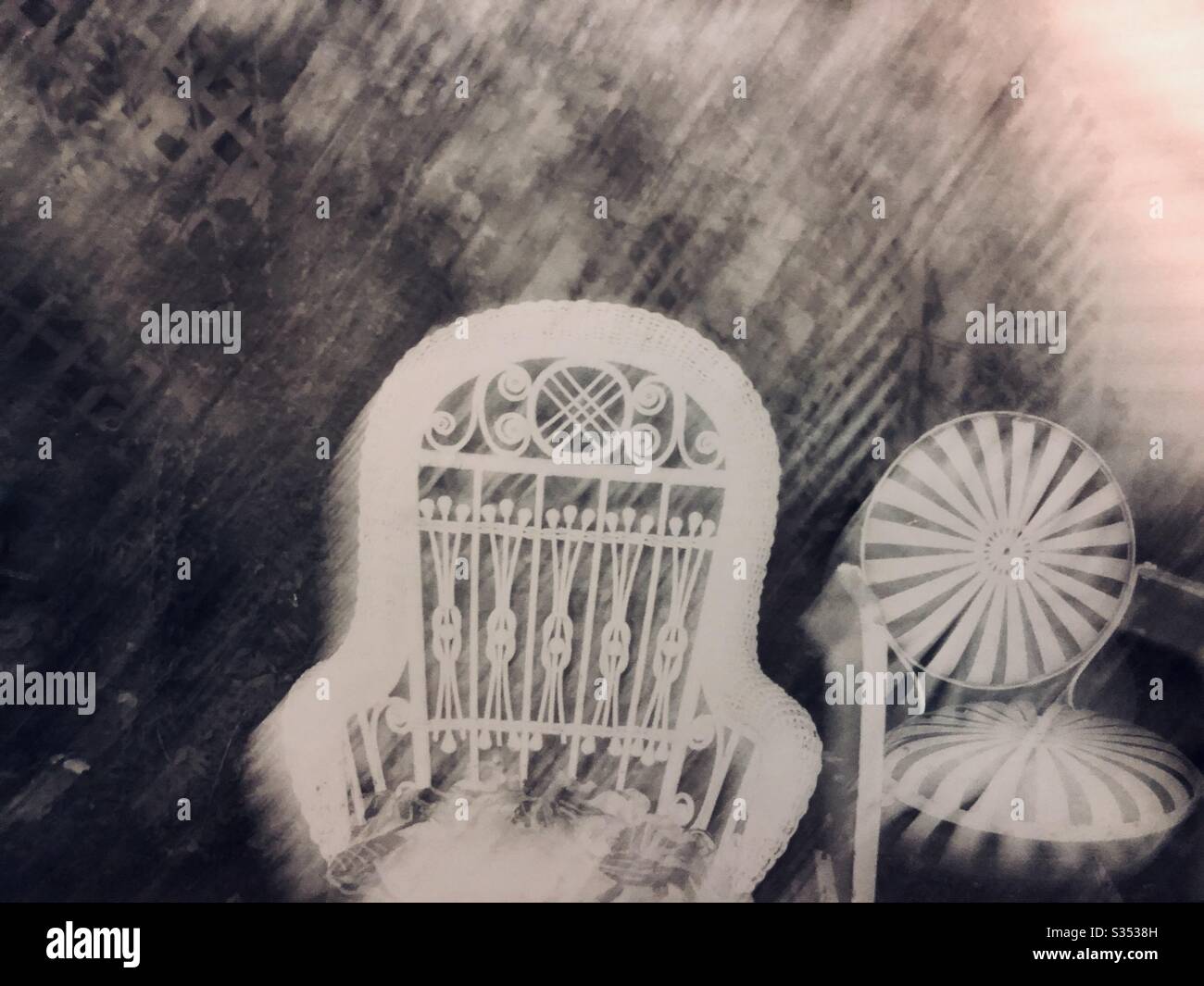 Dreamlike blurred wicker rocking chair and metal chairs in lush empty garden black and white photography - Smartphone Captured Stock Image