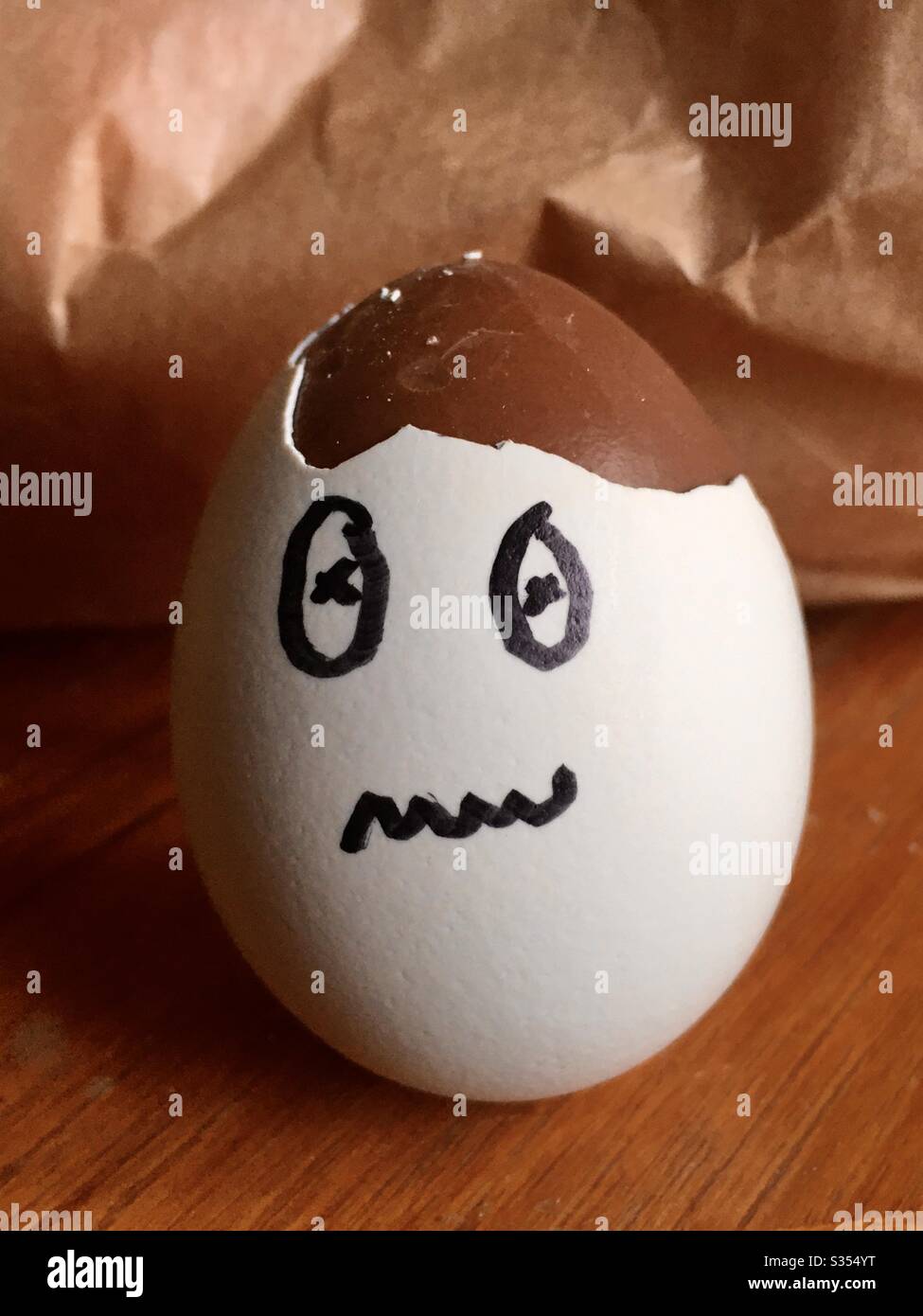 A broken eggshell with a face drawn on it and chocolate inside - Smartphone Captured Stock Image