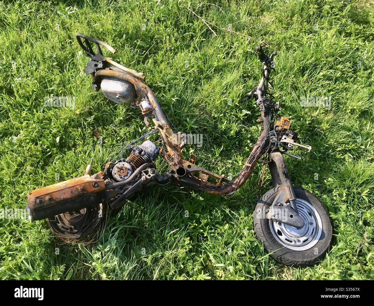 A burnt out motorbike scooter lies on the ground, Bristol, England - Smartphone Captured Stock Image