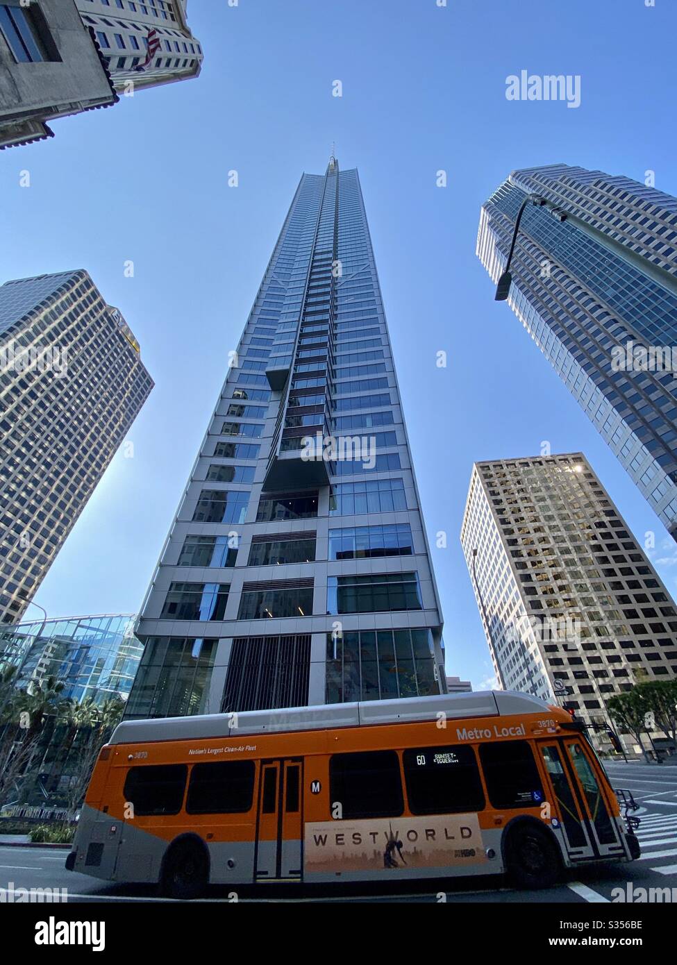 LOS ANGELES, CA, MAR 2020: wide angle view, orange LA Metro Bus passing the Wilshire Grand skyscraper in Downtown on clear, sunny day - Smartphone Captured Stock Image