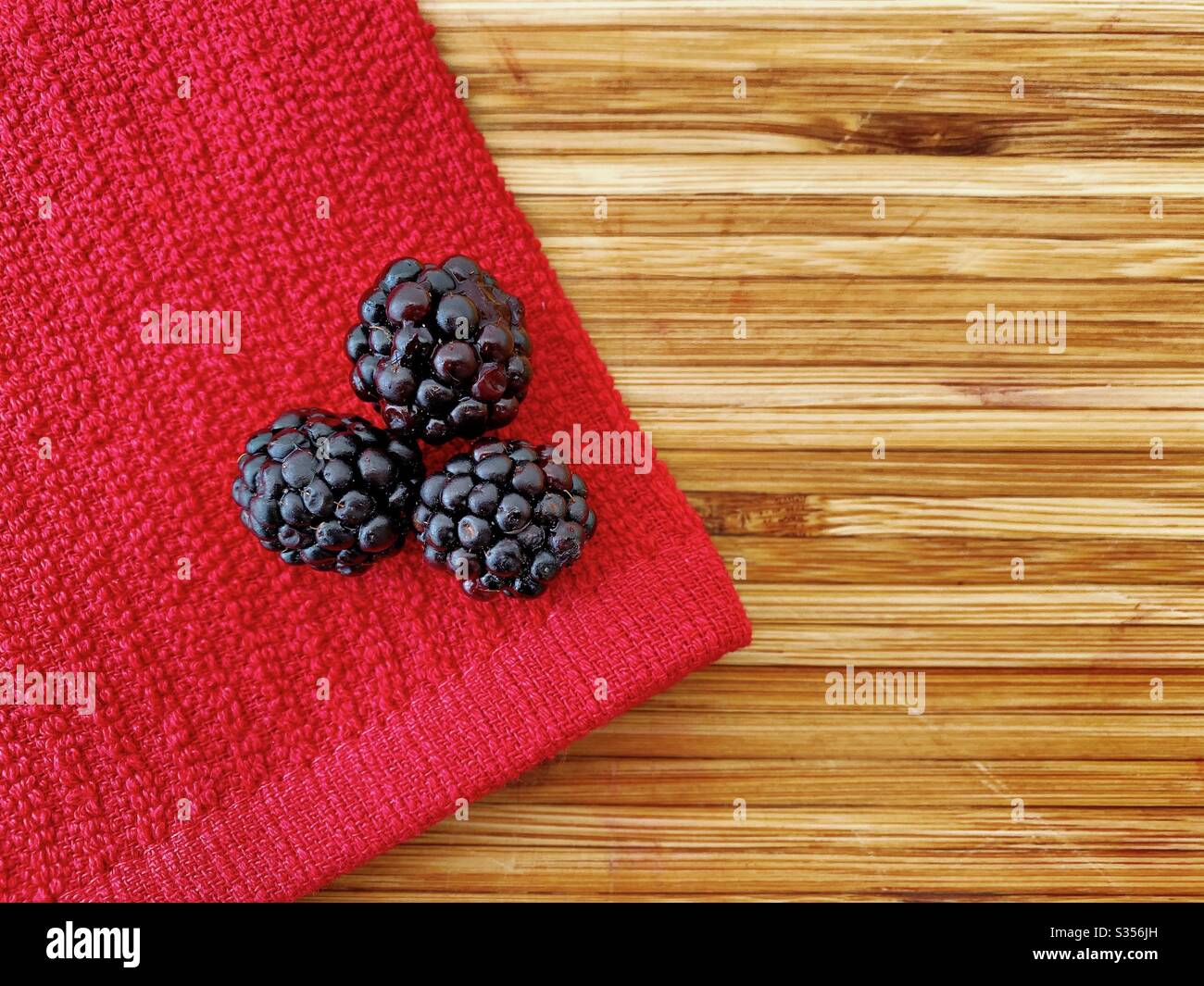 blackberries on a wooden kitchen counter. Ingredients for baking a summer berry, strawberry and blackberry pie. - Smartphone Captured Stock Image