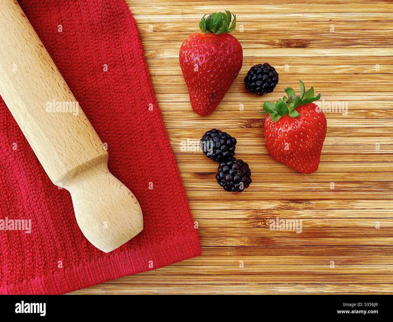 Strawberries and blackberries on a wooden kitchen counter. Ingredients for baking a summer berry, strawberry and blackberry pie. - Smartphone Captured Stock Image