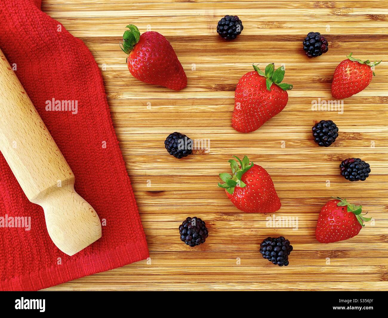 Strawberries and blackberries on a wooden kitchen counter. Ingredients for baking a summer berry, strawberry and blackberry pie. - Smartphone Captured Stock Image