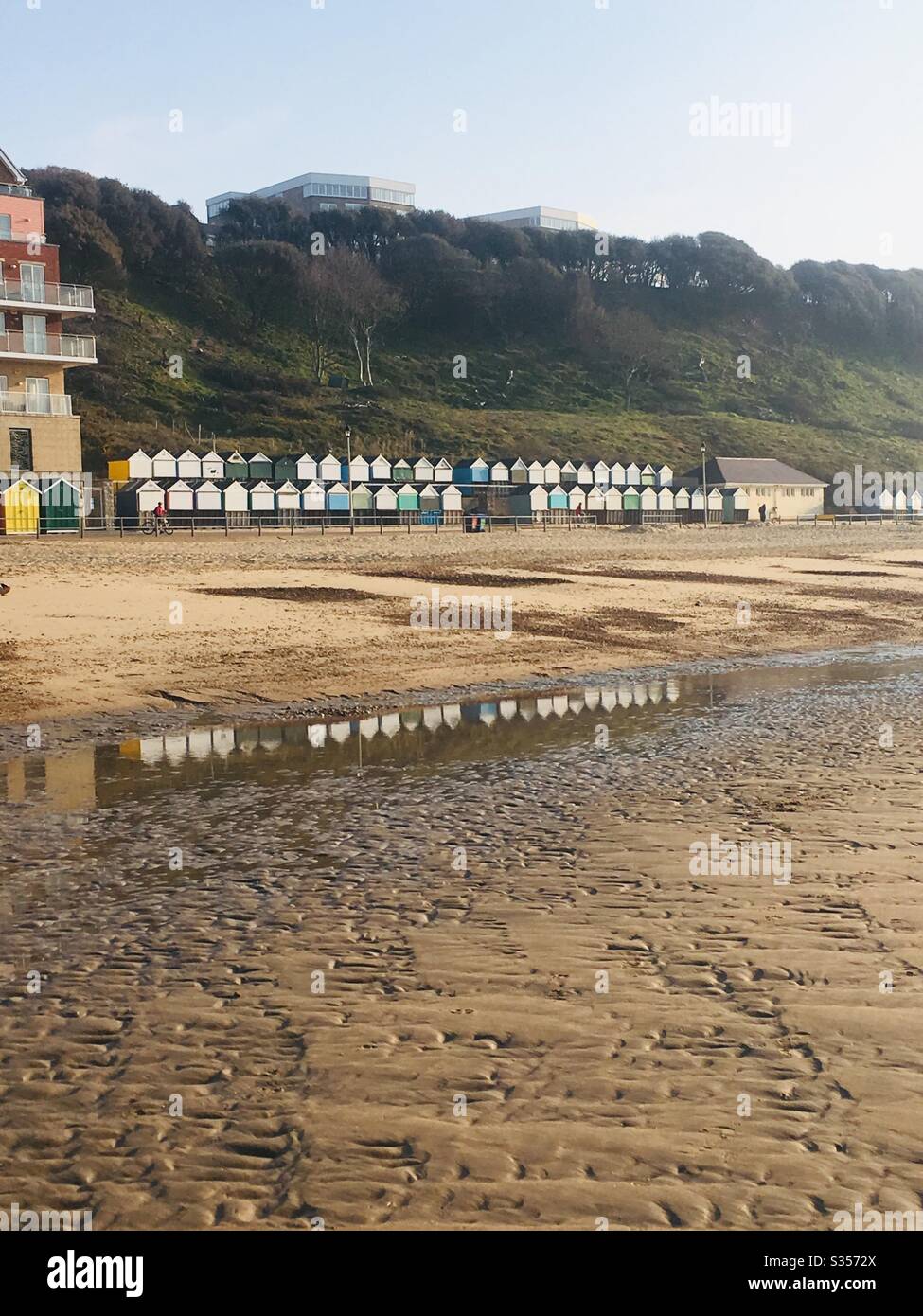 Beach hut reflections in the sand at low tide on Boscombe Beach, Dorset, UK Stock Photo