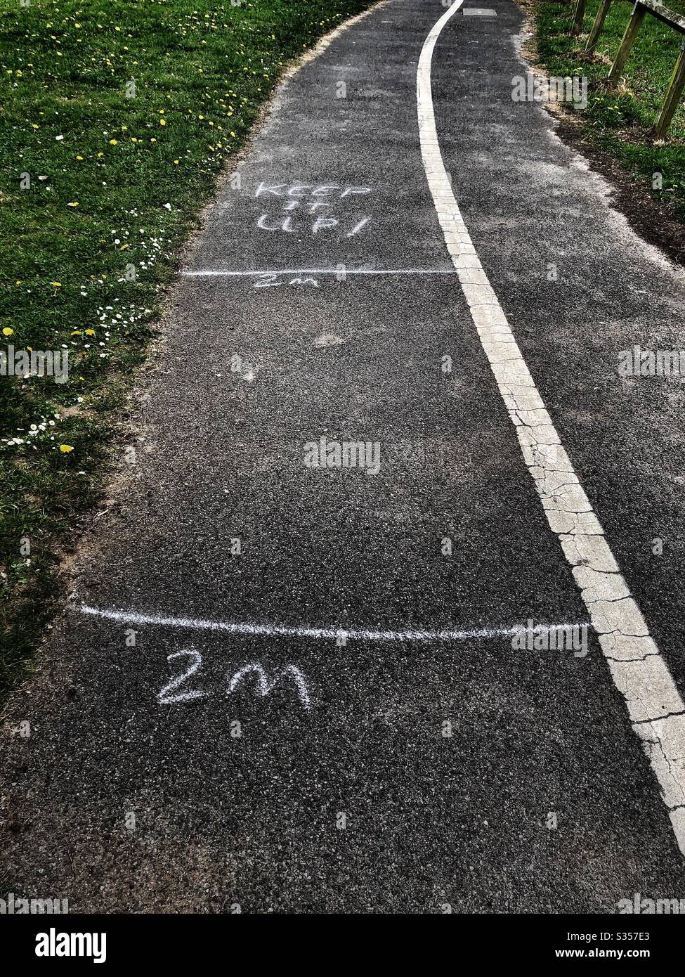 UK coronavirus COVID-19 lockdown 2020 - Chalked message on footpath sidewalk pavement with 2m 2 metres 6ft 6 foot spacing social distancing “Keep it up!” - Smartphone Captured Stock Image