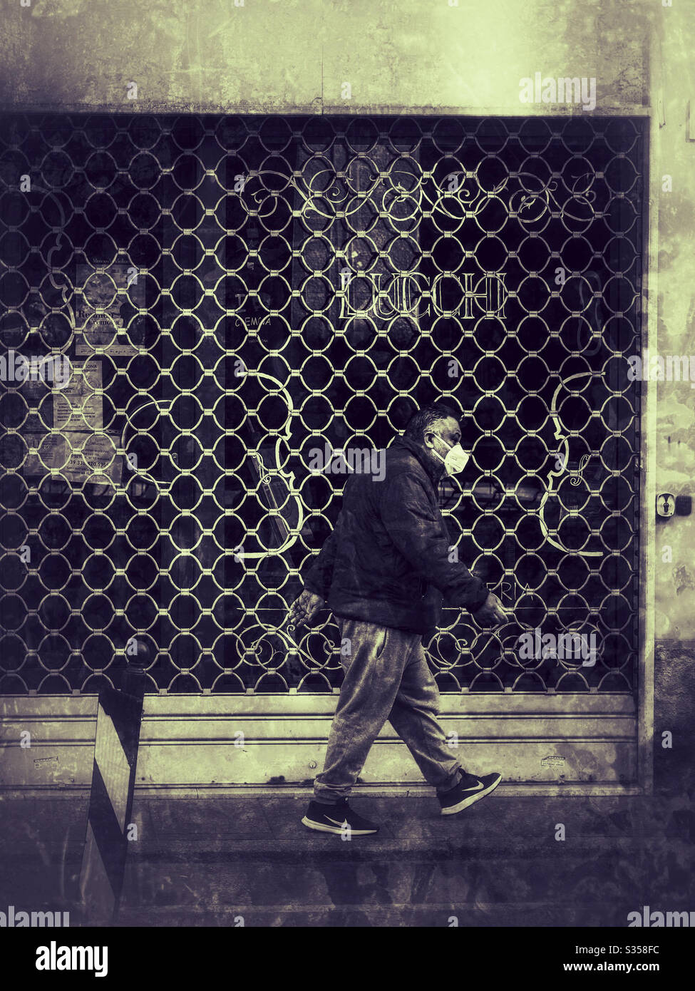 Man wearing a face mask walking in the street and a closed store during lockdown - Smartphone Captured Stock Image