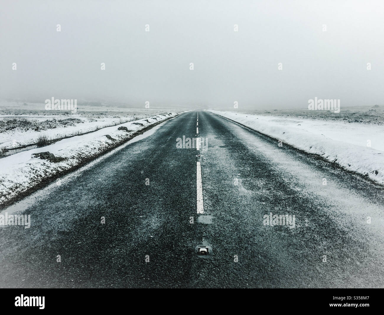 Road through Dartmoor National Park in winter with snow, ice snd fog. Devon, England - Smartphone Captured Stock Image