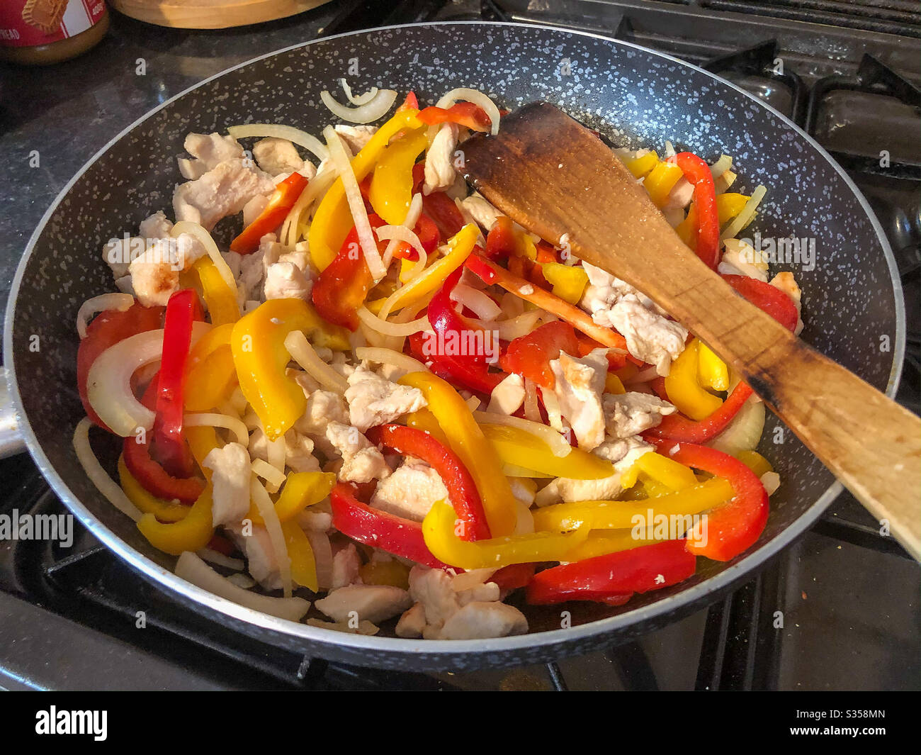 Stir frying sliced chicken, red and yellow peppers and onions in a wok. - Smartphone Captured Stock Image Stir frying sliced chicken, red and yellow peppers and onions in a wok. - Smartphone Captured Stock Image