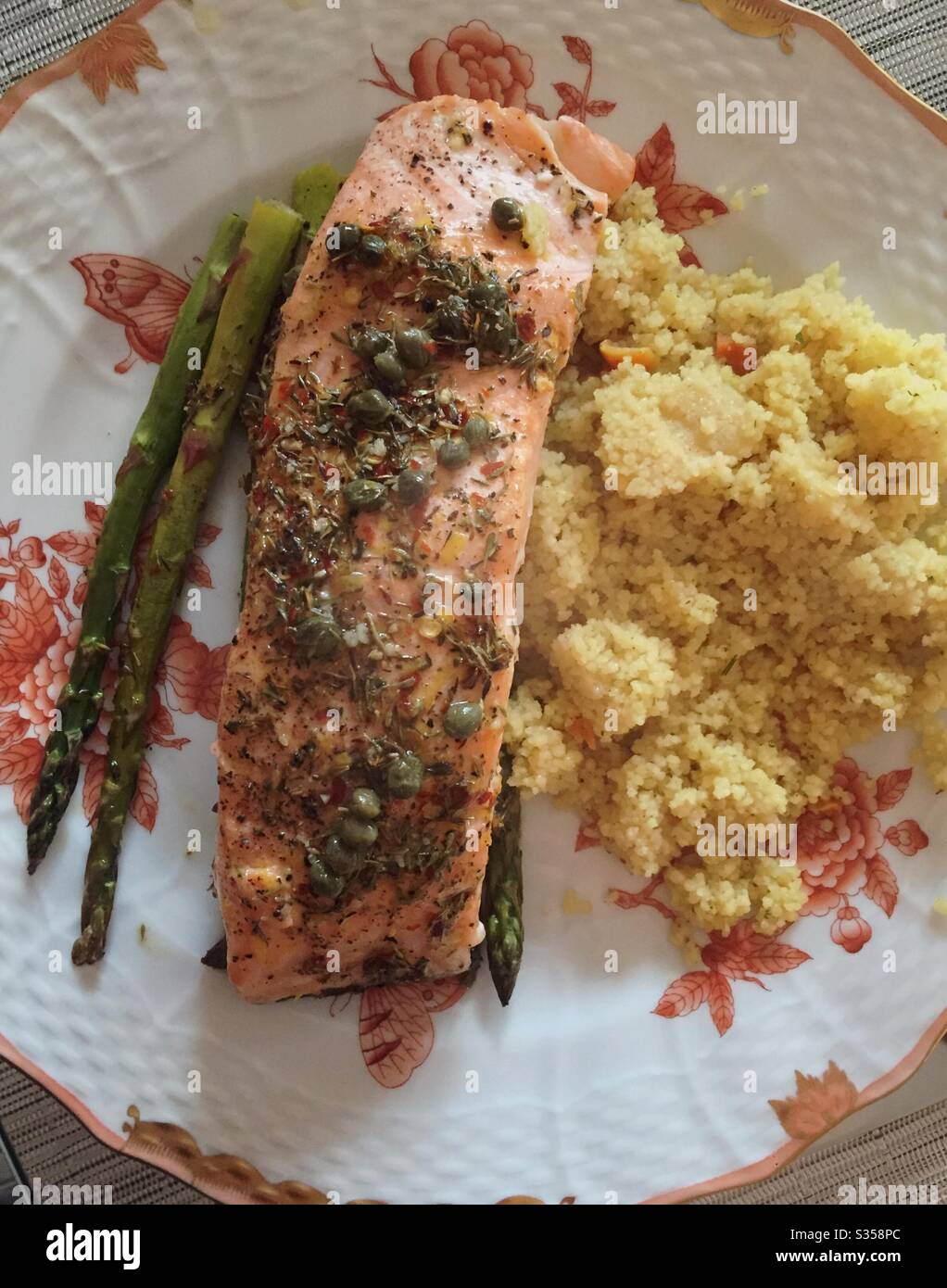 A well-balanced meal of baked salmon, Asparagus and couscous on a patterned china plate - Smartphone Captured Stock Image