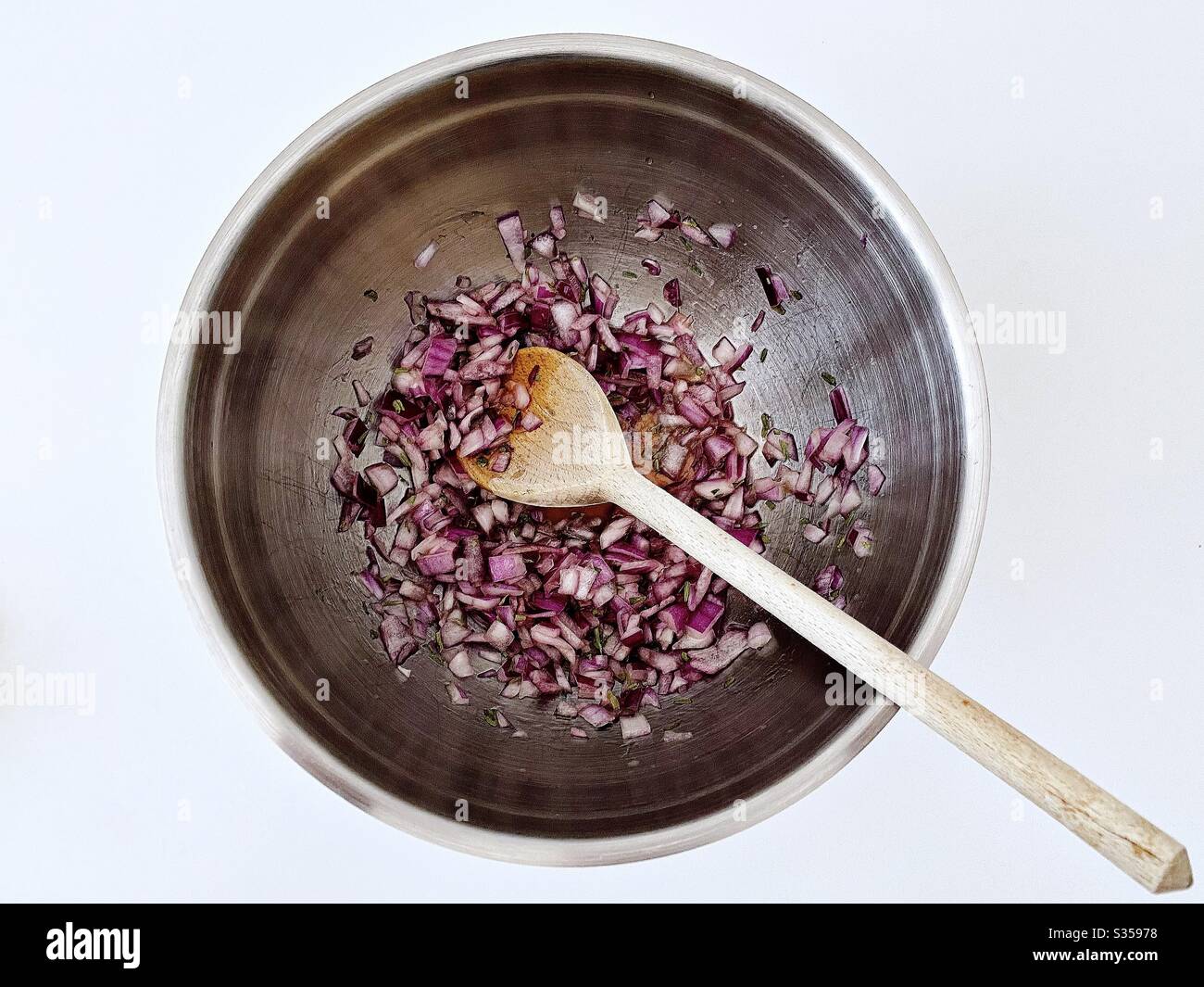 Preparing homemade salsa with red onion, lime juice and coriander in the kitchen. Freshly chopped and mixed in steel bowl. Ingredients for pineapple salsa In mixing bowl. Home recipe prepping. - Smartphone Captured Stock Image