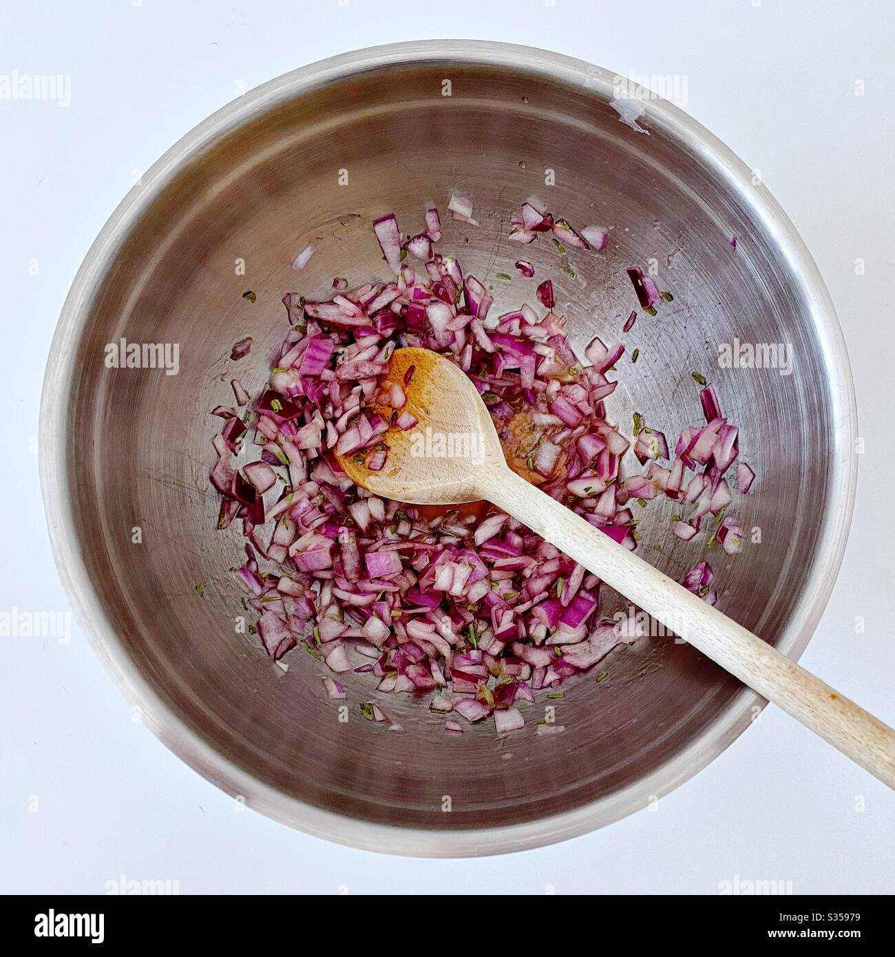 Preparing homemade salsa with red onion, lime juice and coriander in the kitchen. Freshly chopped and mixed in steel bowl. Ingredients for pineapple salsa In mixing bowl. Home recipe prepping. - Smartphone Captured Stock Image