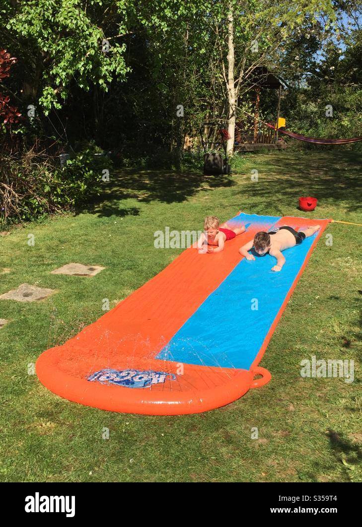 Two boys playing on a slip and slide Stock Photo Alamy