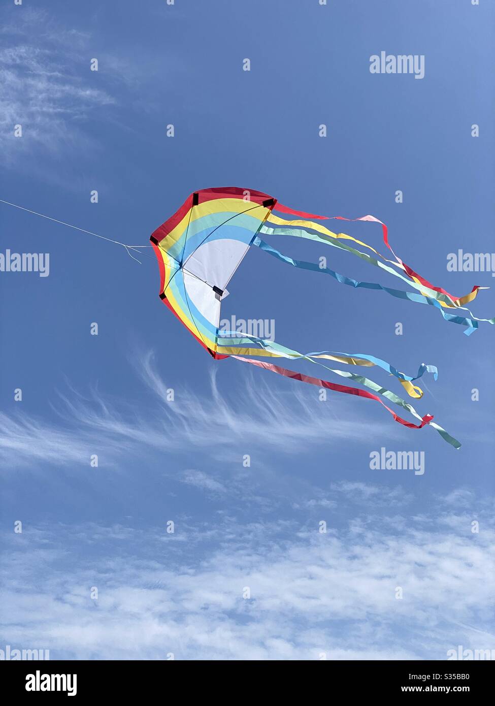 Colorful rainbow kite flying in beautiful blue sky background - Smartphone Captured Stock Image Colorful rainbow kite flying in beautiful blue sky background - Smartphone Captured Stock Image