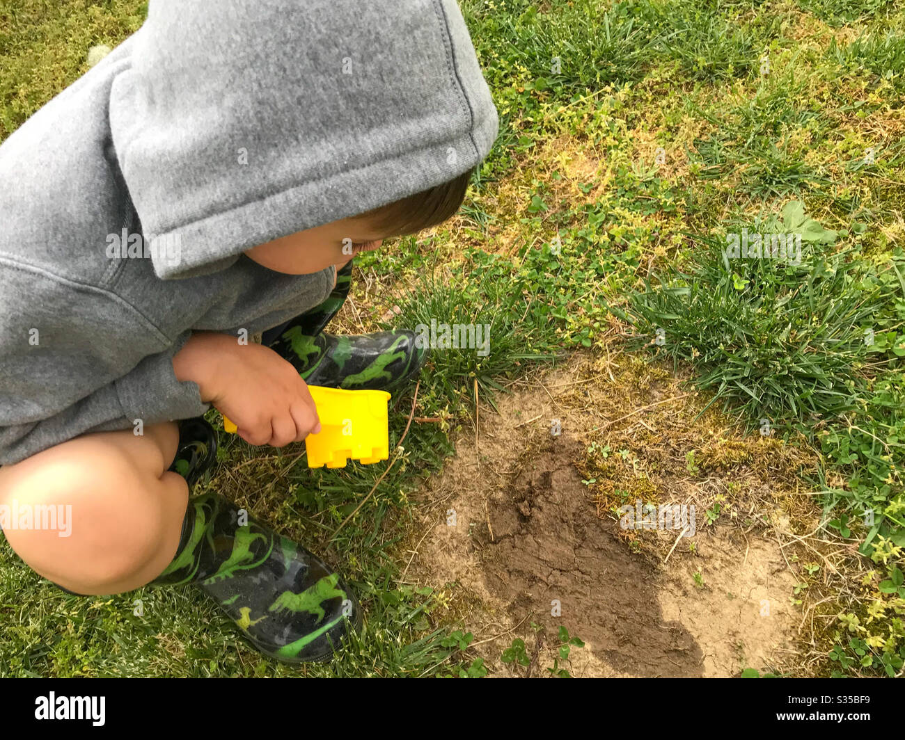 Preschooler little boy looking at a muddy puddle in the yard Stock Photo