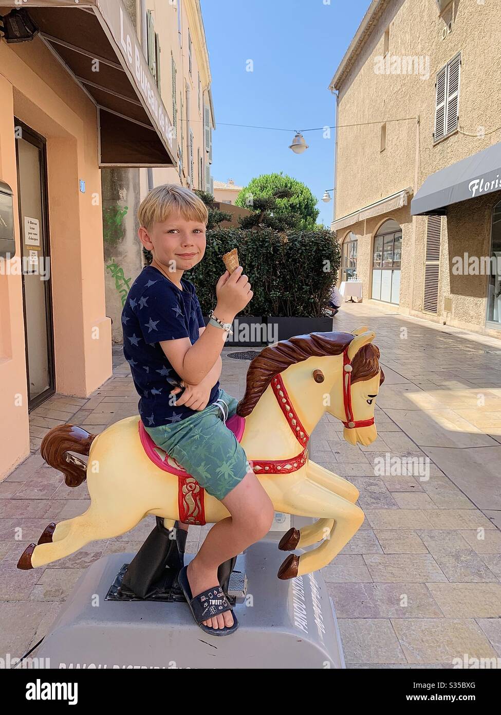 Boy on a coin operated horse, St Tropez, France - Smartphone Captured Stock Image