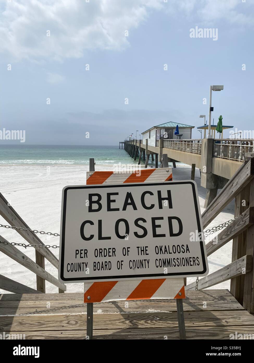 Beach closed sign on Okaloosa Island Florida with public fishing pier in the background due to coronavirus April 8, 2020 USA - Smartphone Captured Stock Image