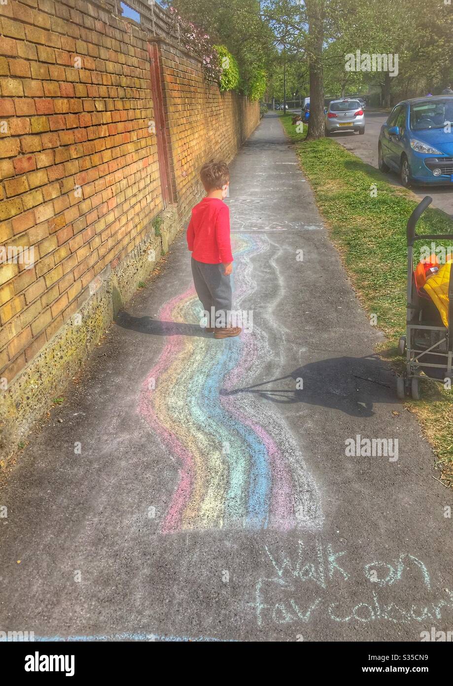 Toddler child walking on chalk obstacle course rainbow lockdown activity - Smartphone Captured Stock Image