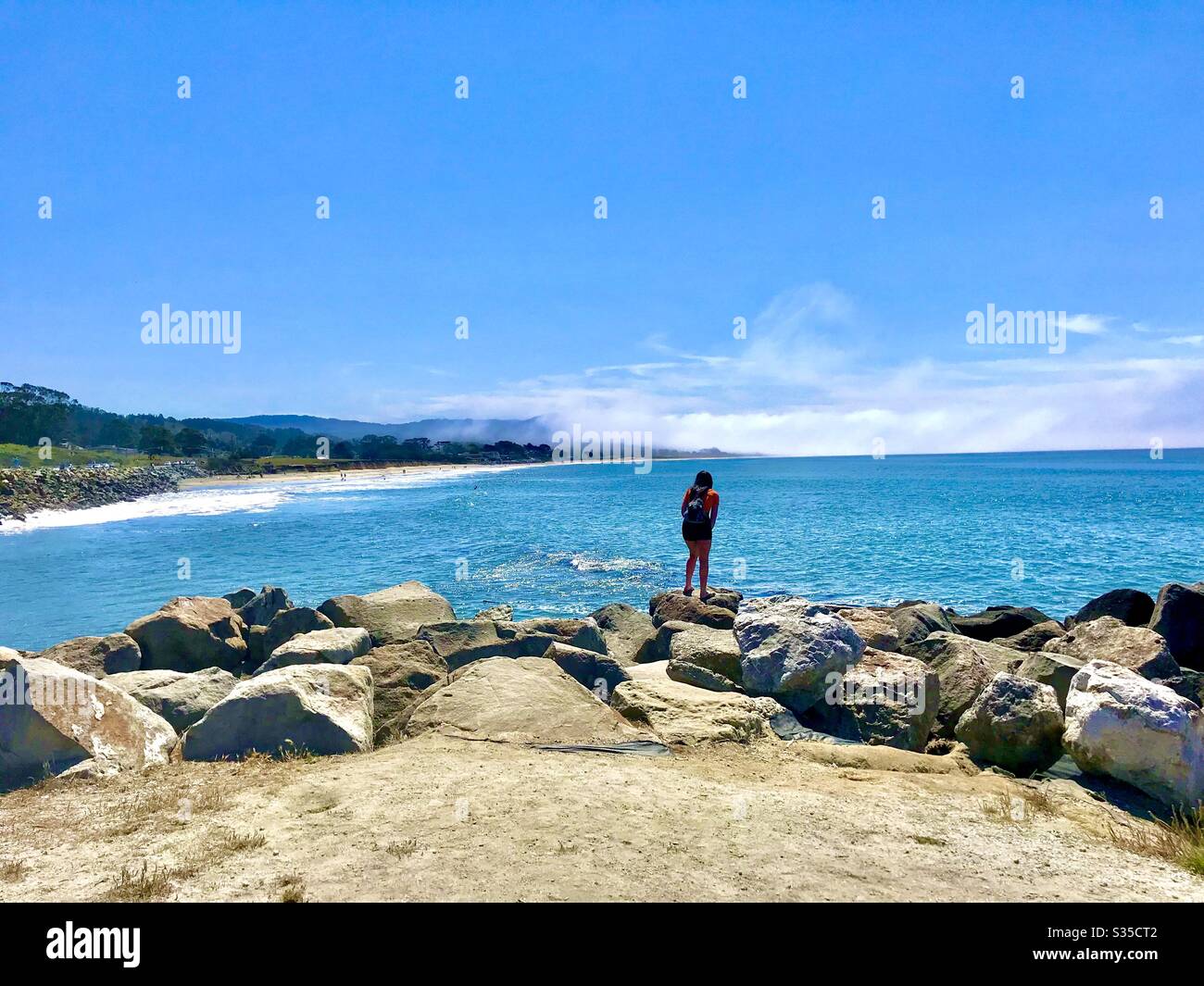 Half moon bay and woman on rocks Stock Photo