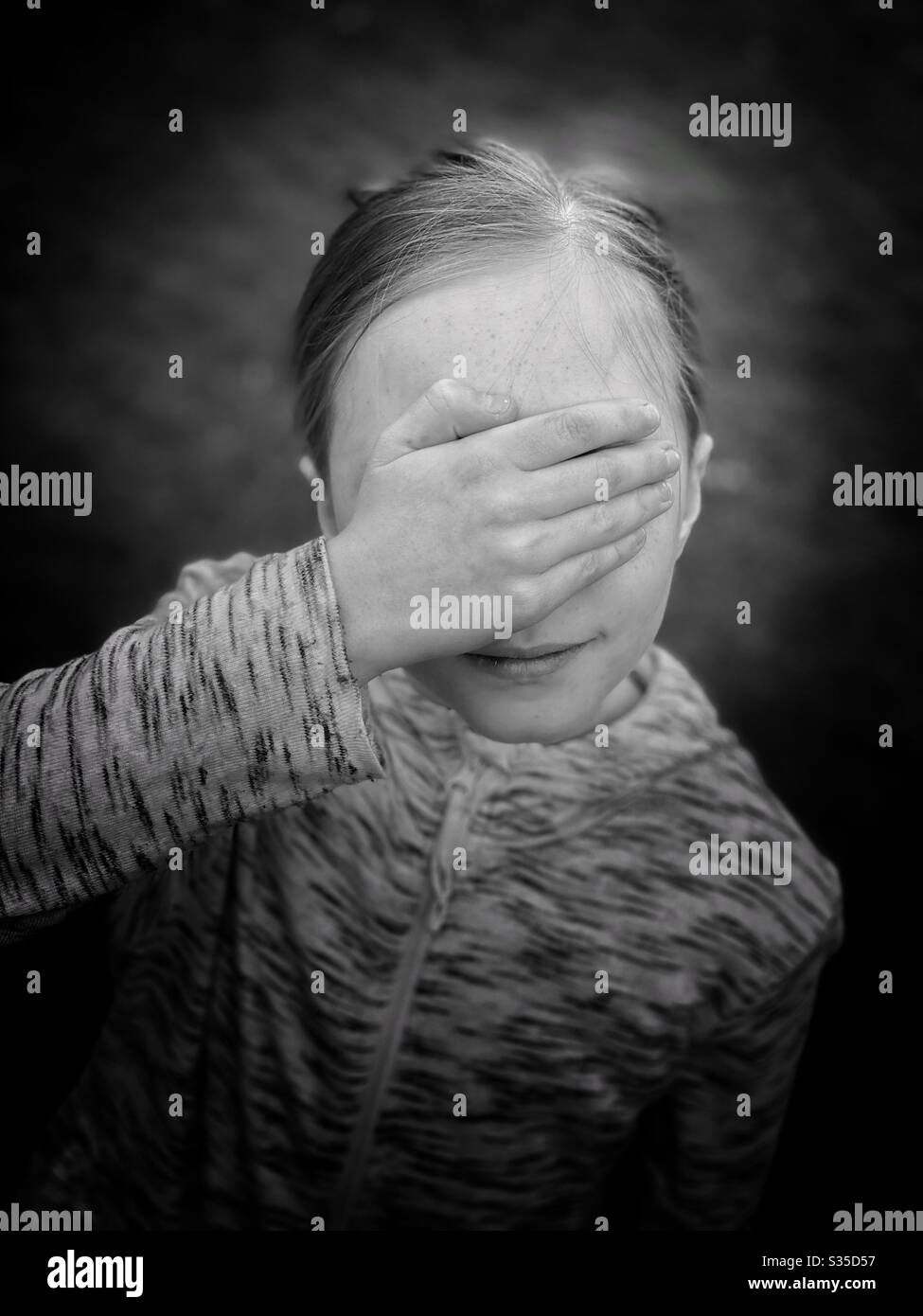 Using her right hand, a child covers her eyes. Why? Photo Credit - ©️ COLIN HOSKINS. - Smartphone Captured Stock Image