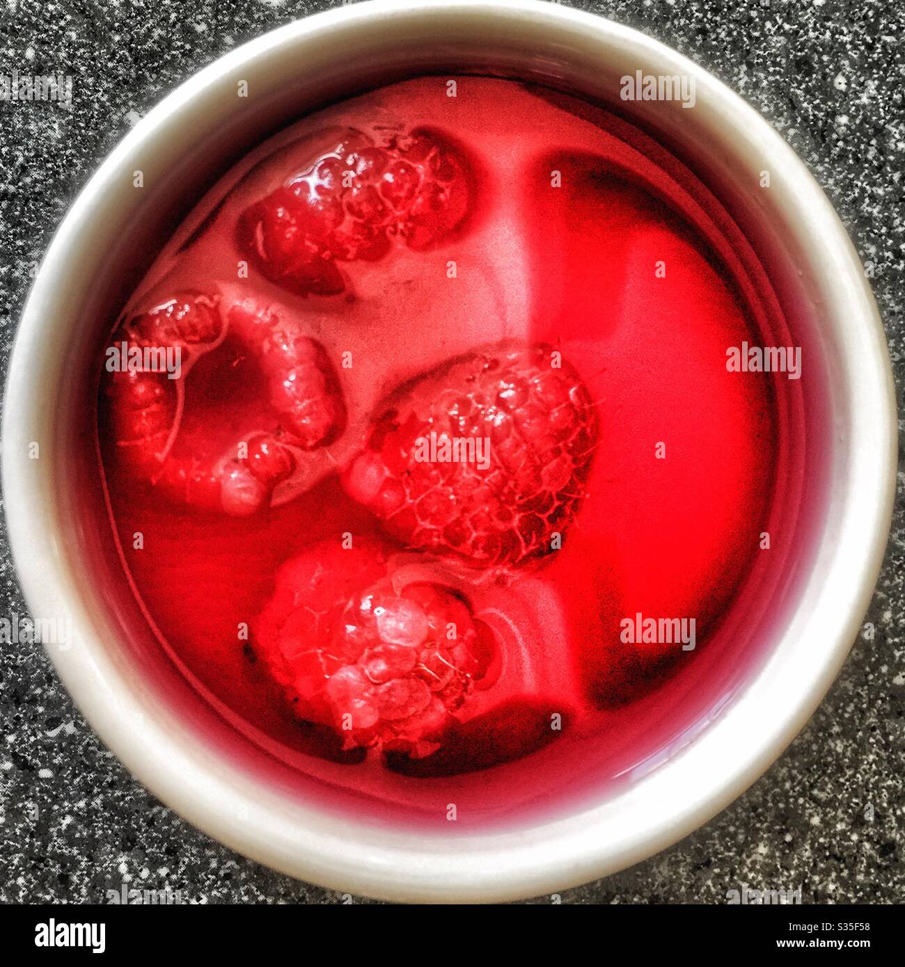 Raspberries in raspberry jelly in a white ramekin dish circle red - Smartphone Captured Stock Image