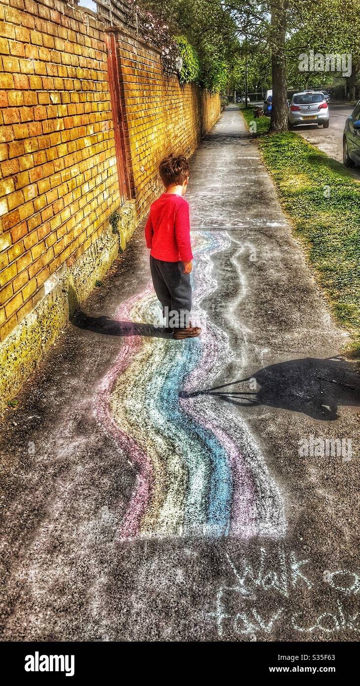Toddler child walking on chalk rainbow activity circuit during daily exercise in lockdown April 2020 - Smartphone Captured Stock Image