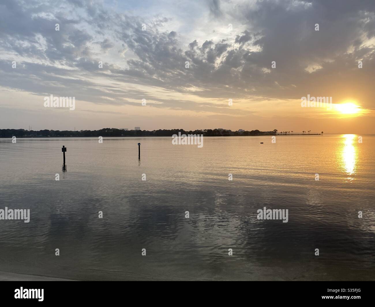 Golden sunset reflecting over calm still bay water Stock Photo - Alamy