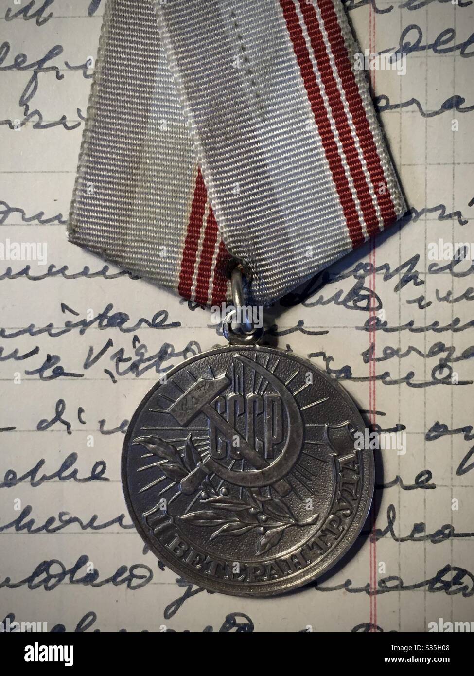 Old Russian ex CCCP commemorative war honor medal on a page of notebook hand written Stock Photo