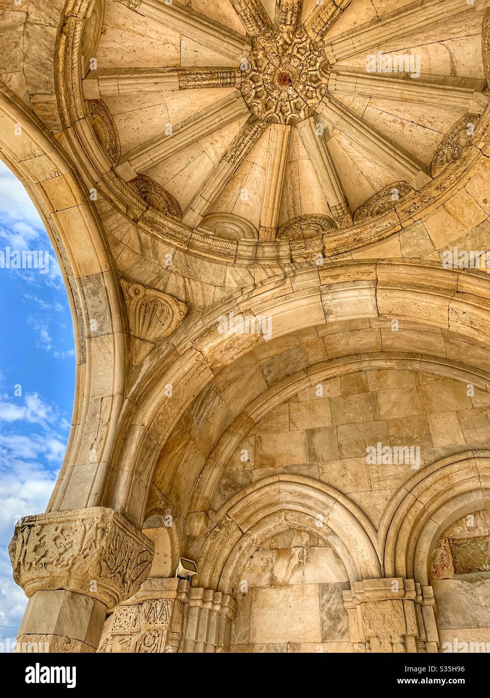 The entrance arch of Gelati Monastery in Kutaisi, Georgia. Beautifully intricate stone carvings against a beautiful blue sky. Stock Photo