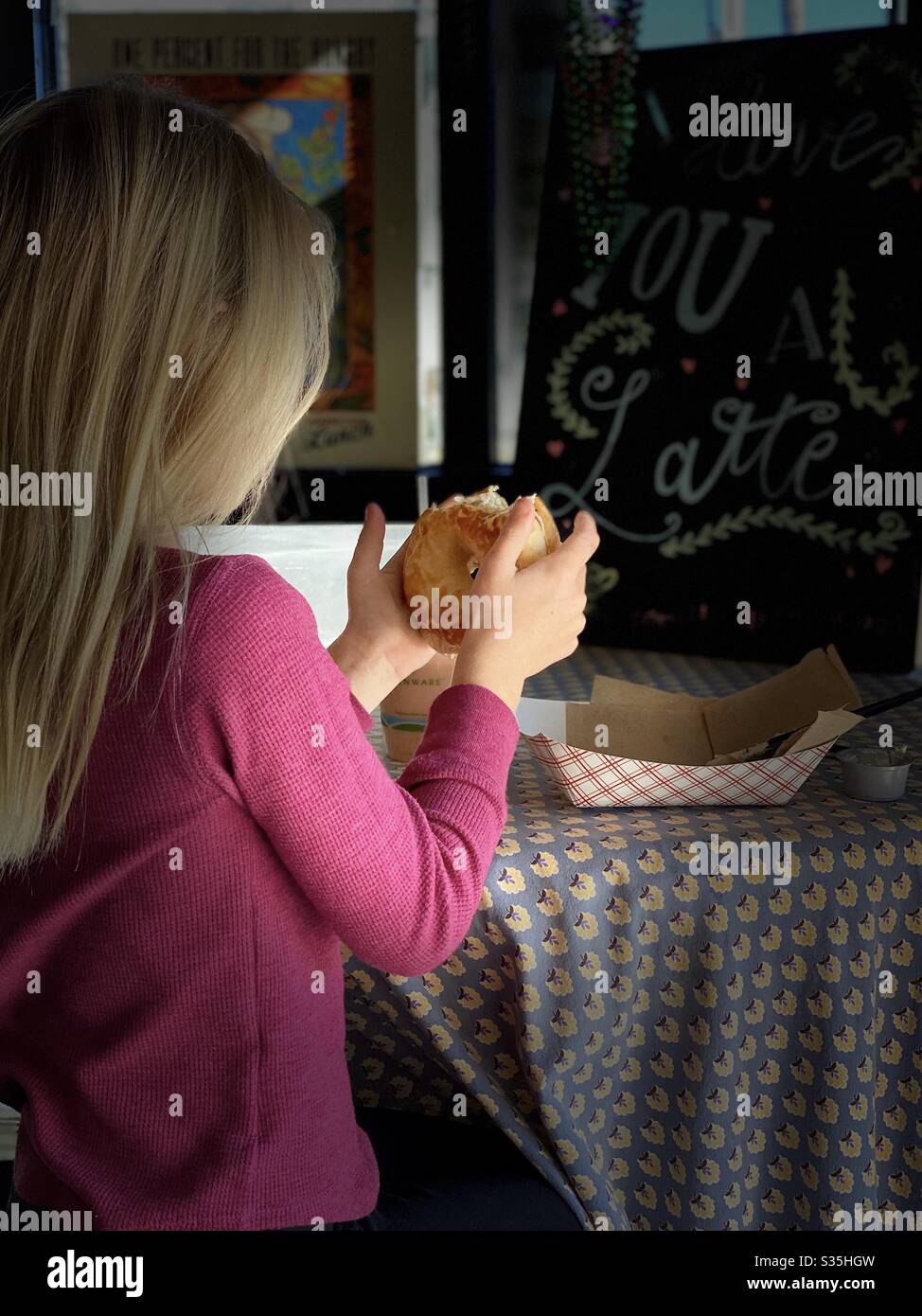 Little girl enjoying a donut in a coffee shop portrait Stock Photo