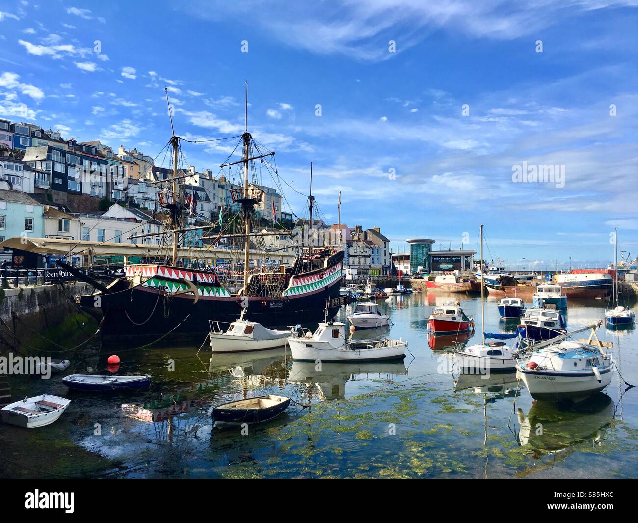 The beautiful fishing harbour of Brixham on a summers day. Pleasure boats, a replica of the Golden Hind and harbour side properties. - Smartphone Captured Stock Image