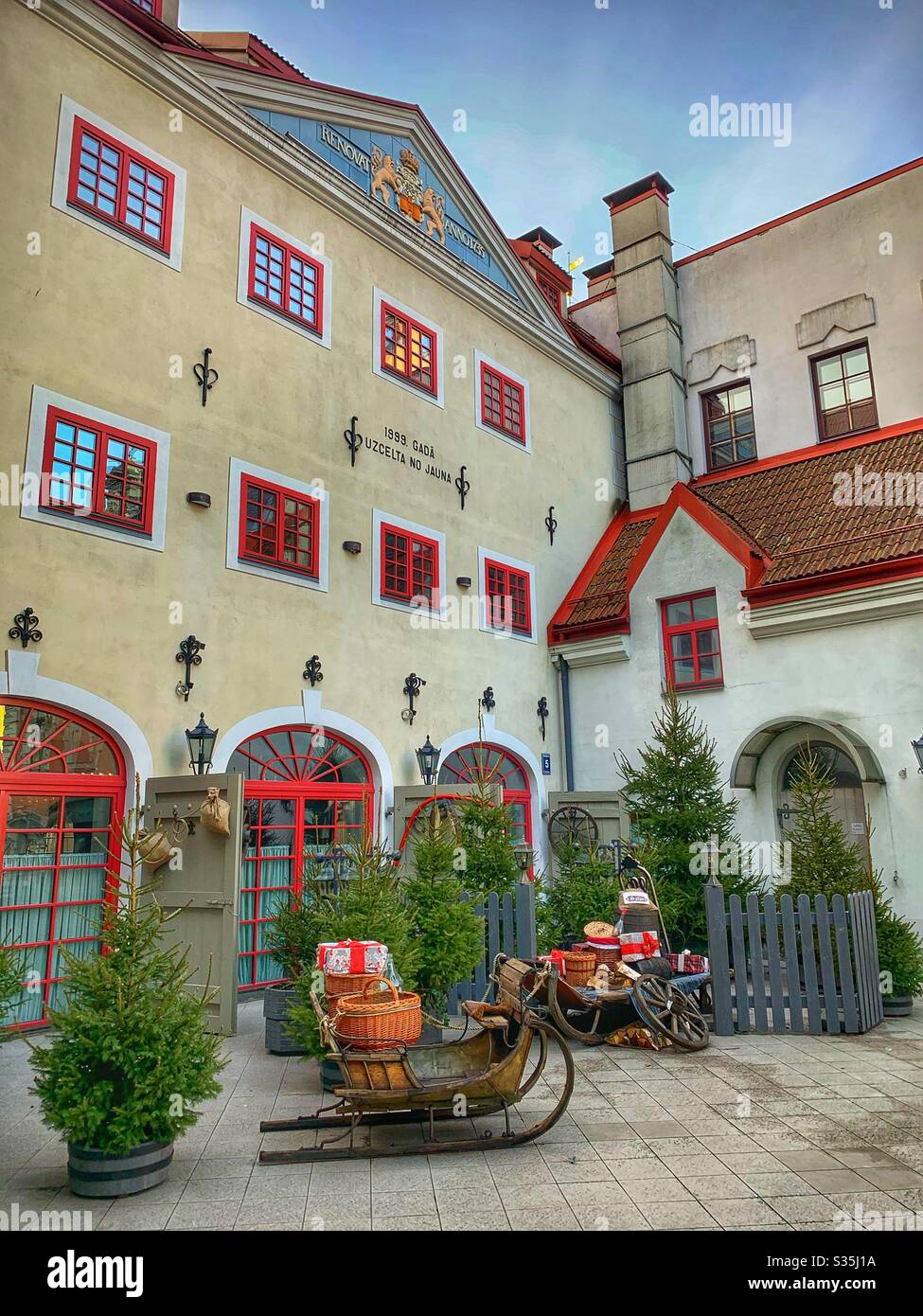 Christmas Sledding Scene in front of an unusual yellow and red building in Riga, Latvia. - Smartphone Captured Stock Image