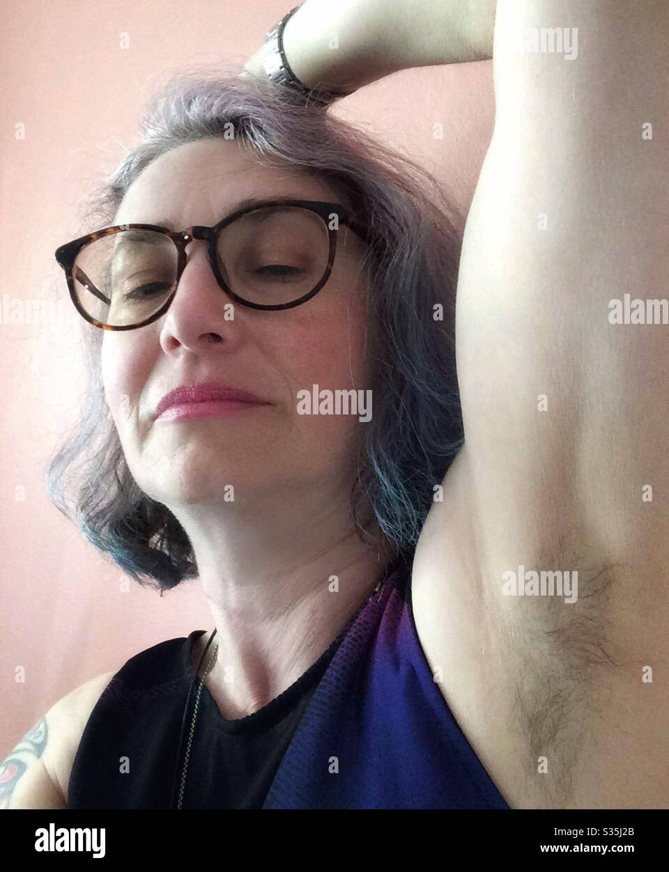 Middle aged woman with bobbed pastel dyed hair, showing a hairy armpit. Stock Photo