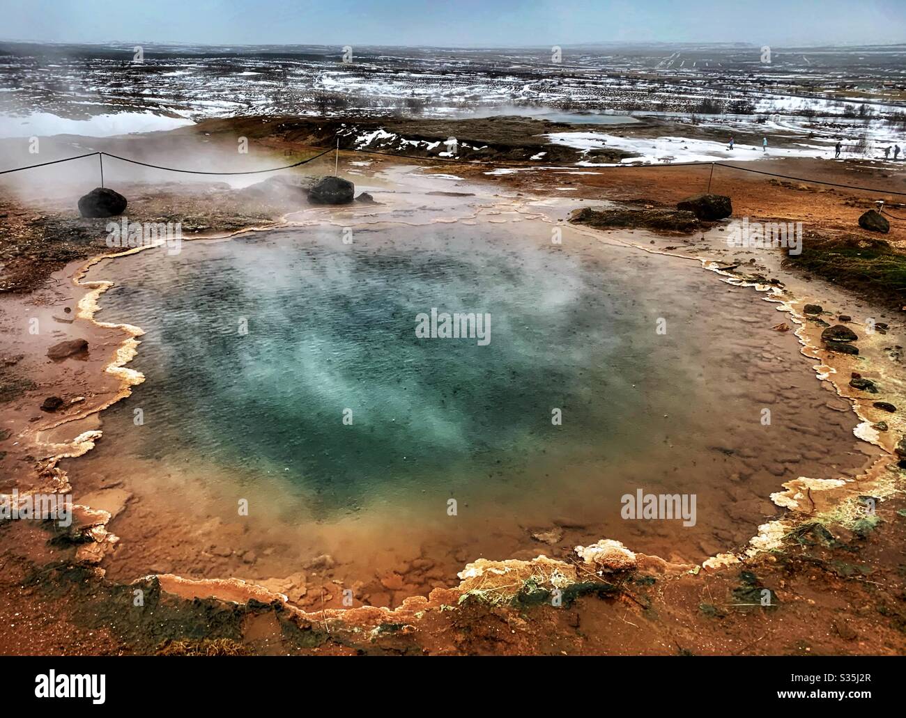 A colourful Geothermal Pool in Iceland. Surrounded by a vast snowy landscape. Geyser, Iceland. - Smartphone Captured Stock Image