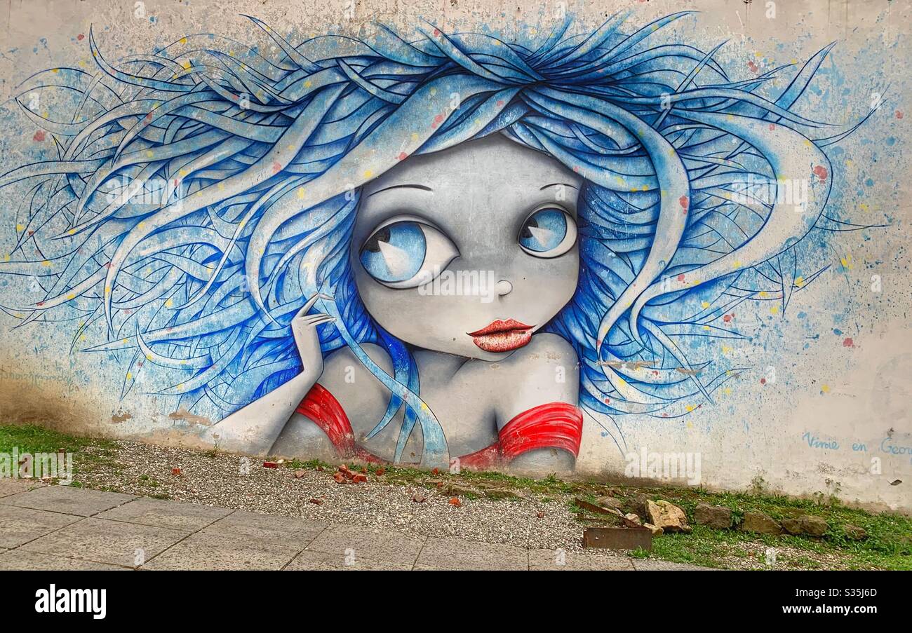 Street art of a girl with huge eyes, blue hair and a red top. Kutaisi, Georgia. - Smartphone Captured Stock Image
