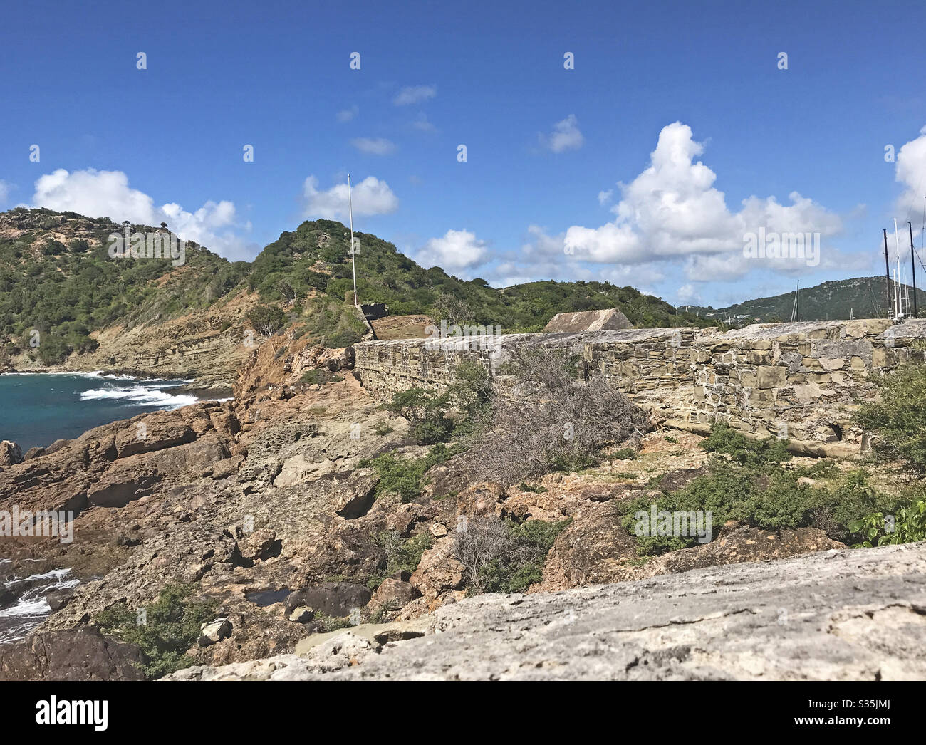 Antigua coastline, outer fort wall and guard house roof as seen from the Fort Berkeley Peninsula in Antigua and Barbuda, Caribbean, Lesser Antilles, West Indies. - Smartphone Captured Stock Image