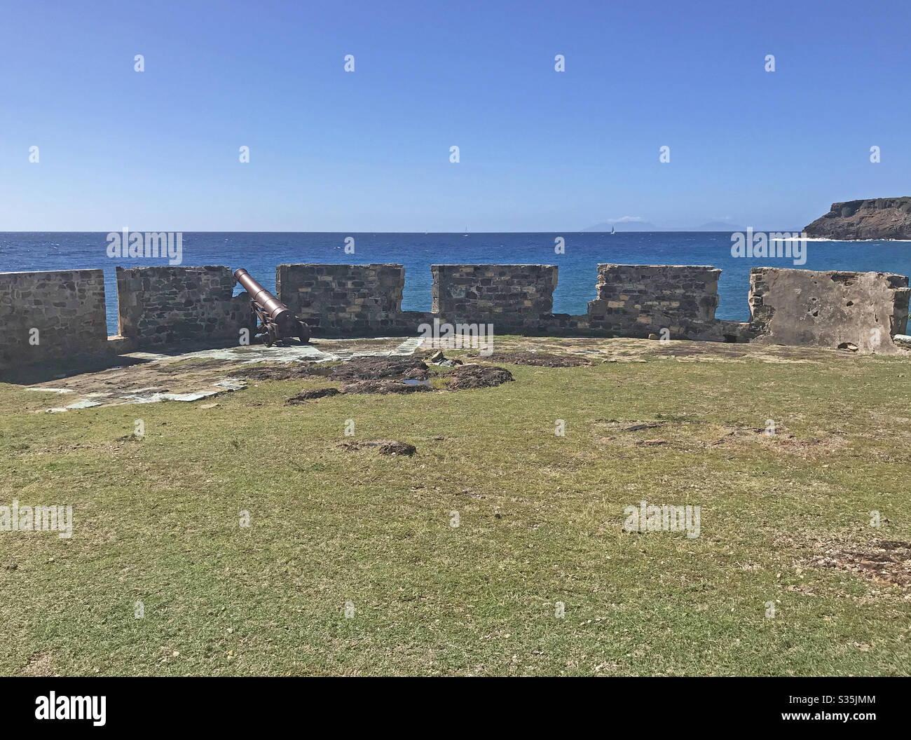 Antigua coastline and outer fort wall with cannon ports as seen from the Fort Berkeley Peninsula in Antigua and Barbuda, Caribbean, Lesser Antilles, West Indies with blue sky copy space. - Smartphone Captured Stock Image