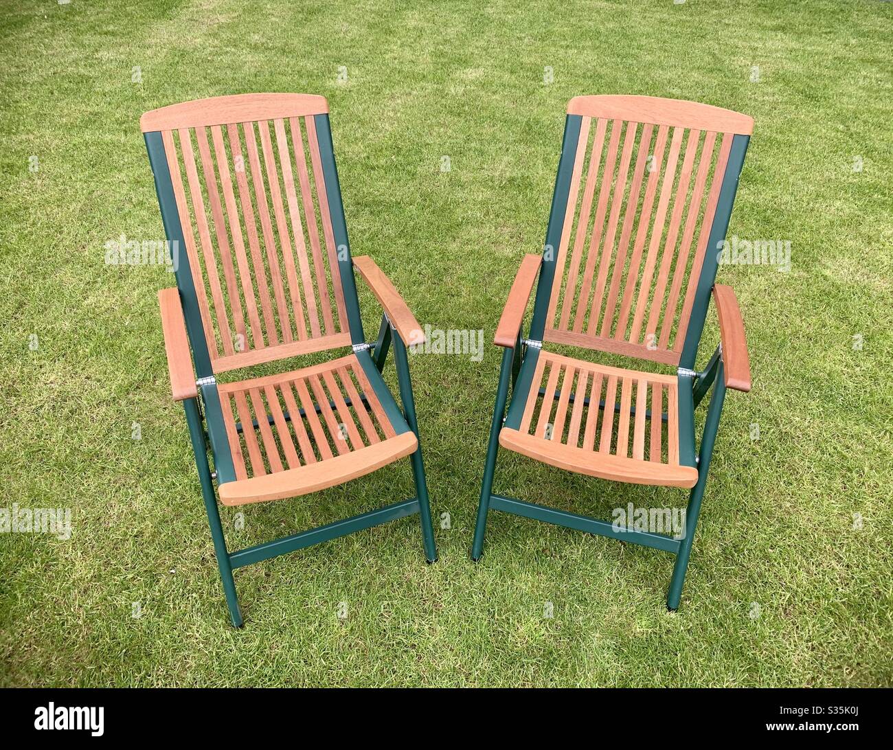 Two wooden garden chairs on a manicured lawn. - Smartphone Captured Stock Image