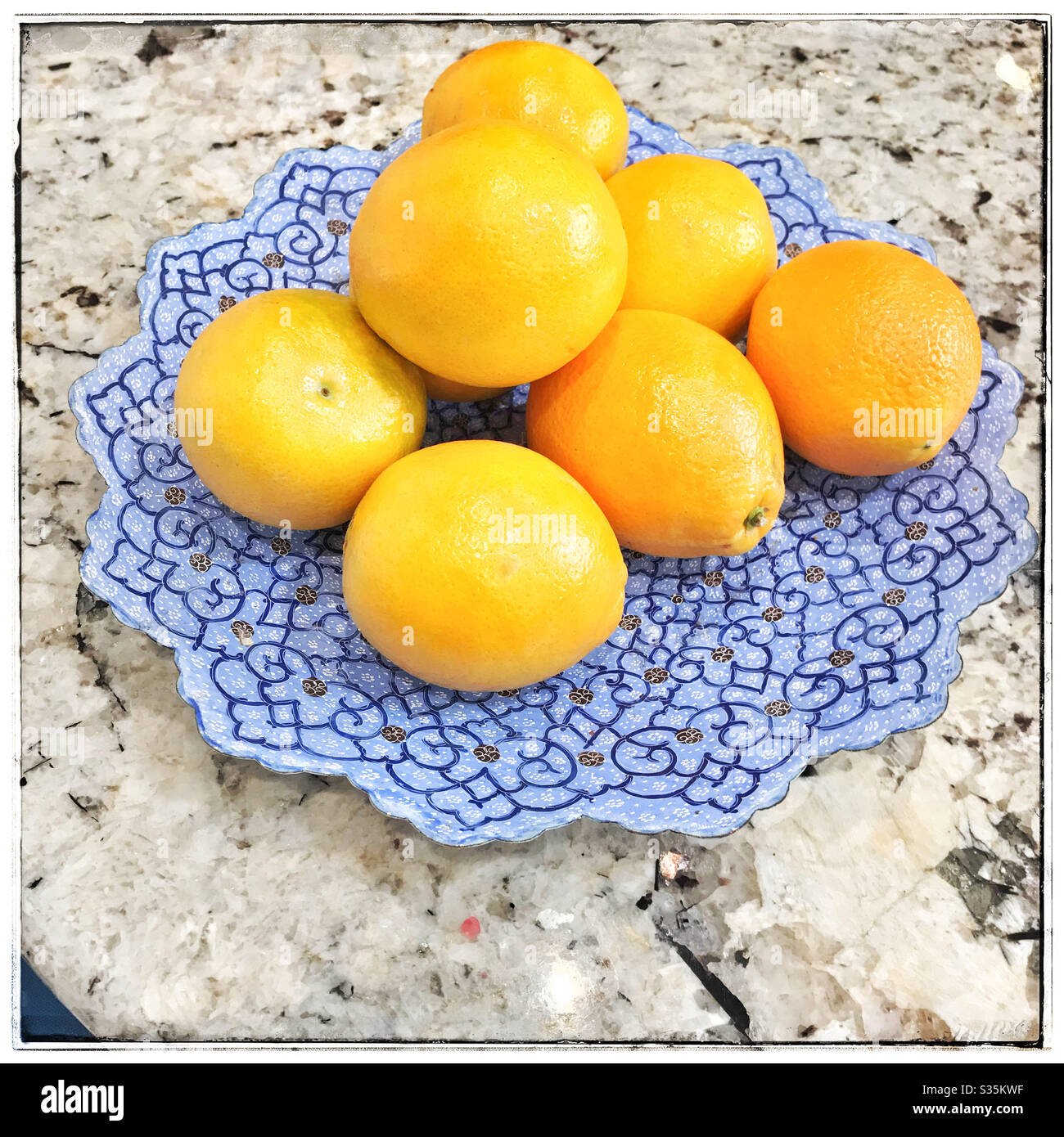 Oranges on a blue plate on table. Stock Photo
