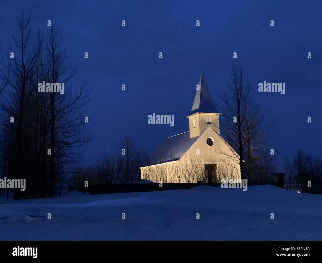 A small and simple church in Iceland in the middle of nowhere, lit up against the dark sky. Blue Hour. - Smartphone Captured Stock Image