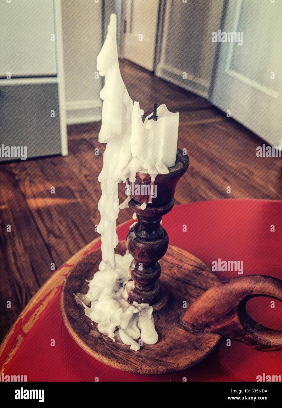 The wax drippings from a candle on  a hand carved wooden candlestick create a sculpture light presentation - Smartphone Captured Stock Image
