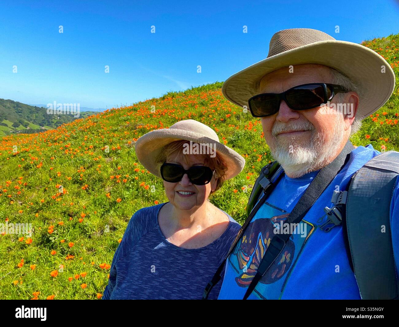 Two seniors on a hike by a field of poppies - Smartphone Captured Stock Image