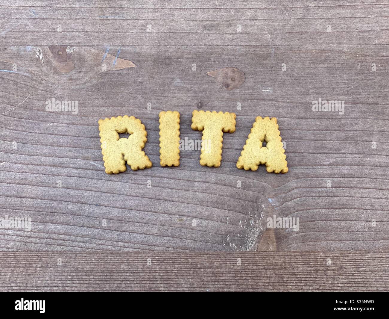 Rita, female given name composed with biscuit letters over a wooden board Stock Photo