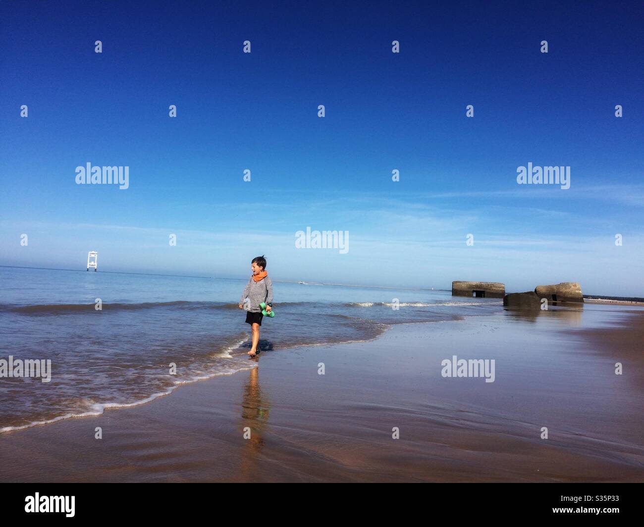 Boy walking on the beach in Royan, France. Staring at sea Stock Photo