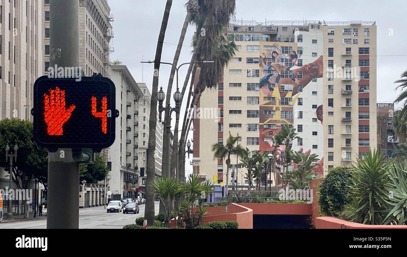 LOS ANGELES, CA, APR 2020: crosswalk sign showing four seconds remaining and a red hand at the corner of Pershing Square in Downtown with apartment buildings in background - Smartphone Captured Stock Image