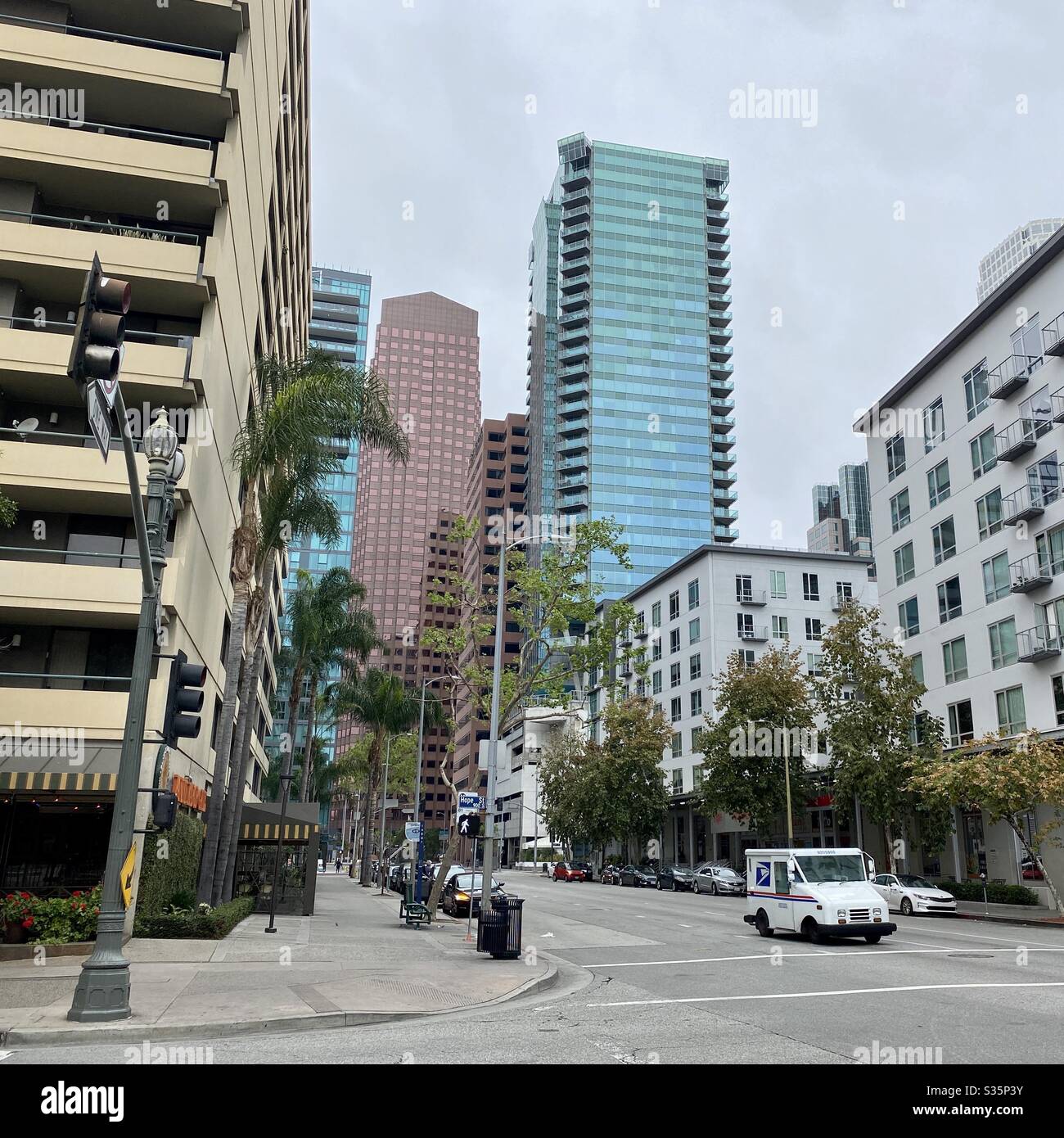 LOS ANGELES, CA, APR 2020: US Post Office van making deliveries in Downtown against backdrop of skyscrapers, offices and apartments. Overcast, cloudy day - Smartphone Captured Stock Image