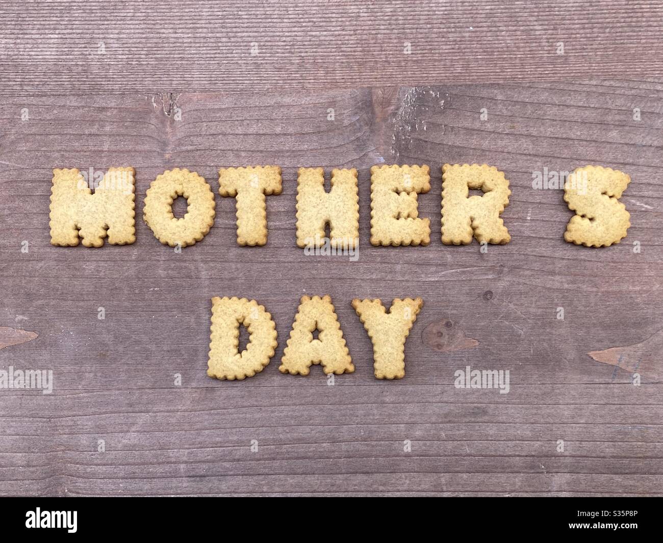 Mother’s Day text composed with cookie letters over a wooden board - Smartphone Captured Stock Image