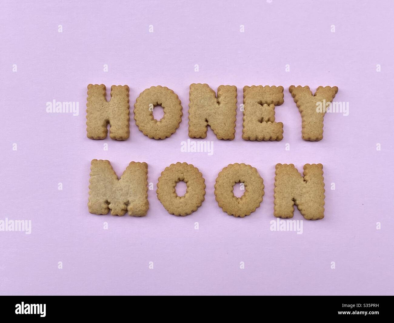 Honeymoon text composed with biscuit letters over pink background - Smartphone Captured Stock Image