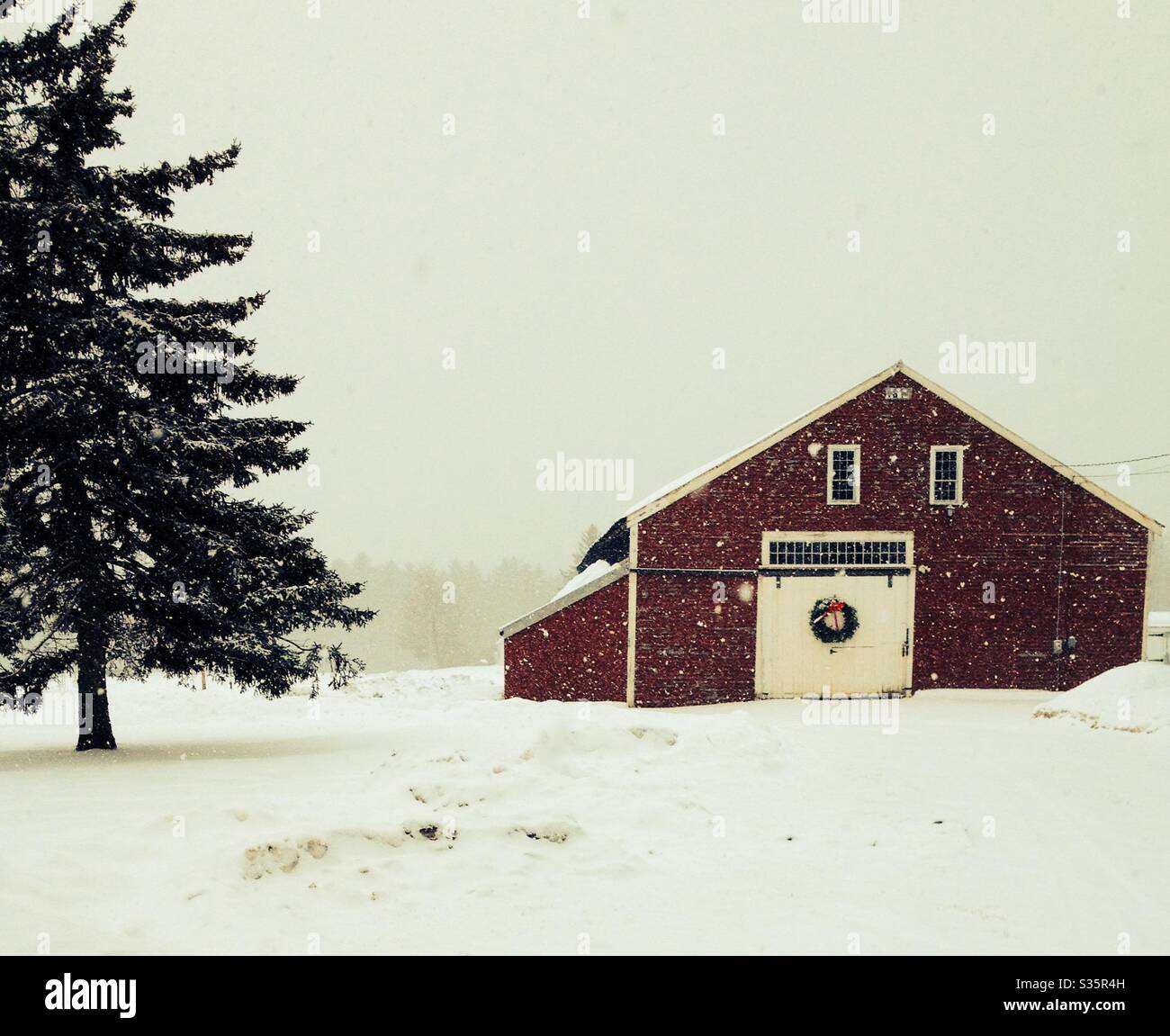 Rural farm house in the snow with a Holiday wreath on the barn door. - Smartphone Captured Stock Image